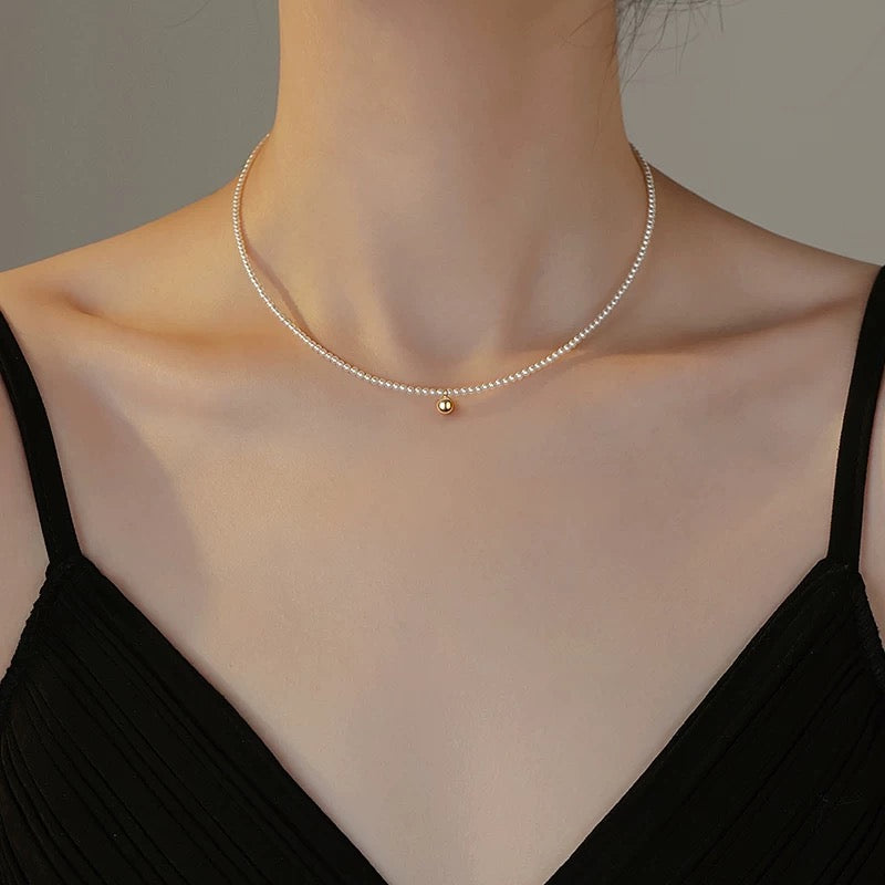 Collier ras-du-cou en perle avec une petite médaille centrale